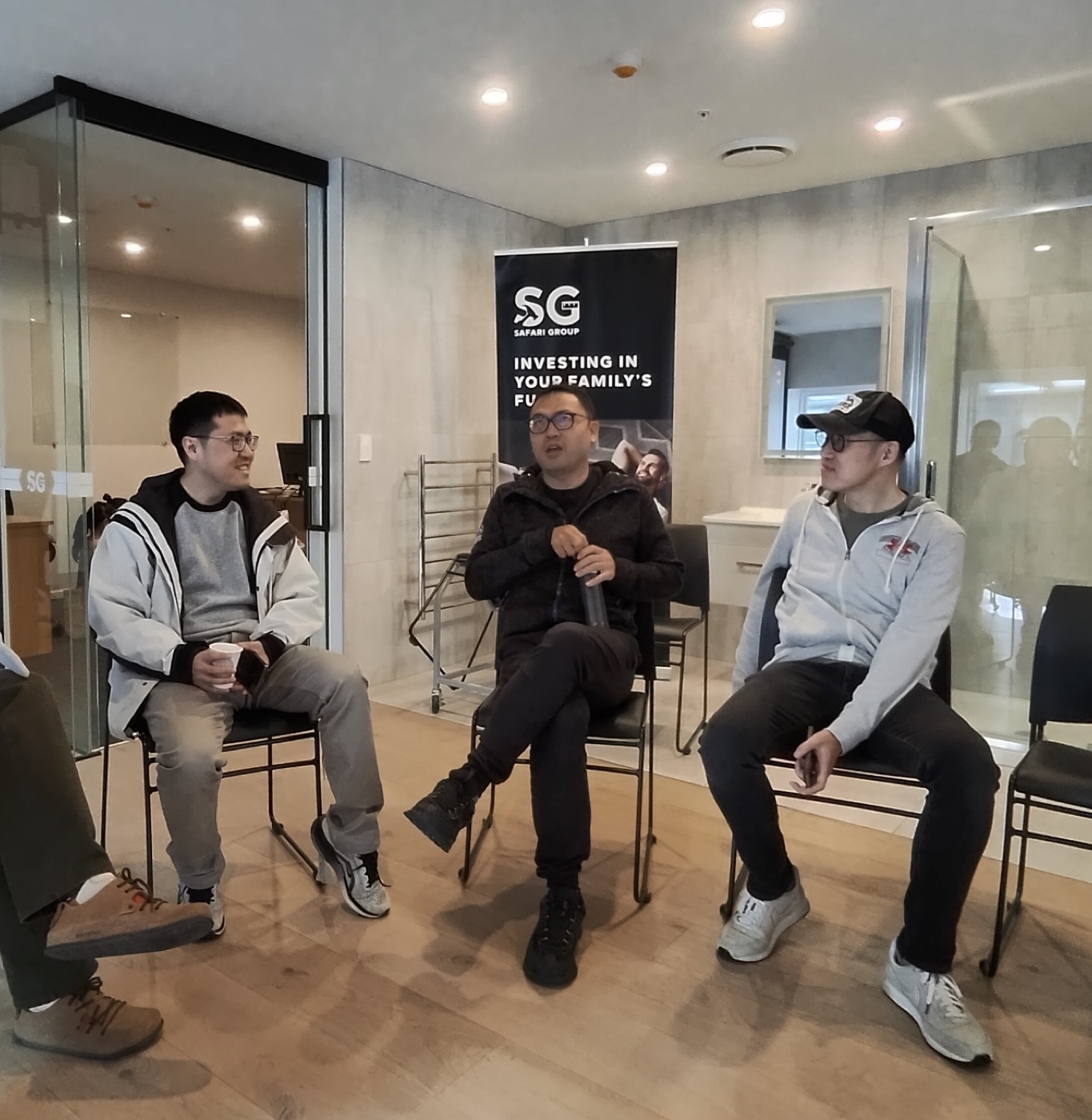 三位参与者在 Safari Group 易拉宝前交谈
